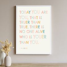 there is a vase with some flowers on the table next to it and a poster that says today you are true than true