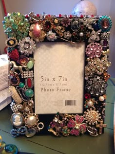 a photo frame with lots of different types of jewelry on it sitting on a table