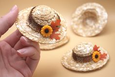 a hand holding a straw hat with sunflowers on it next to other hats