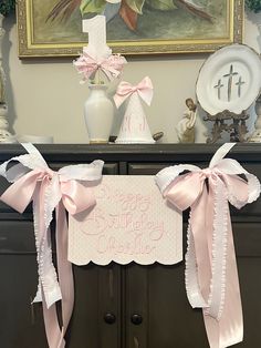 a happy birthday banner with pink bows on top of a dresser next to a vase