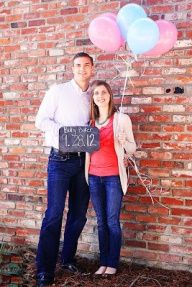 a man and woman standing next to each other with balloons in front of a brick wall