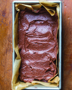 a pan filled with chocolate frosting on top of a wooden table