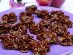 chocolate cookies on a purple plate next to bowls of cereal