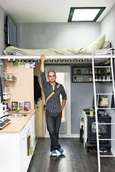 a man standing in front of a bunk bed with a ladder to the loft above him