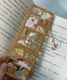 a person holding an open book with some cartoon characters on the front and back cover