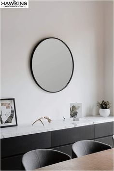 a round mirror hanging on the wall above a table