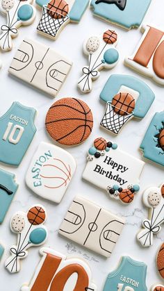 cookies decorated with sports themed icing on a white tablecloth covered in blue and orange decorations