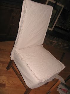 a chair that is sitting on top of a hard wood floor and covered in white fabric