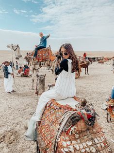 a woman sitting on top of a camel in the desert