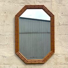 a round mirror mounted to the side of a wall next to a brick wall with a wooden frame