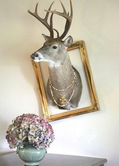 a deer head mounted to the side of a wall next to a vase with flowers