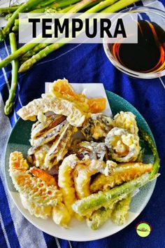 a plate full of food next to asparagus and a cup of tea with the words tempura on it