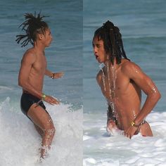 two young men playing in the water at the beach, one with dreadlocks