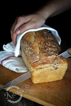 a loaf of bread is being cut on a cutting board with a knife and napkin