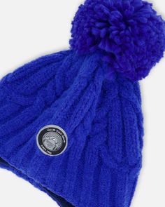 Detailed with a cozy lining, our Peruvian Knit Hat Royal Blue puts the perfect finishing touch on any cold weather look. This adorable winter hat features a chunky cable knit texture with earflaps, a fluffy pompom on top, and braided tassels that hang on each side. Team with a matching neckwarmer for added warmth and total coordination! Earflap hat Pompom Braided tassels 58% Acrylic,15% Nylon, 27% PBT - Lining: 94% Polyester, 6% Elastane Fits true to size From 2 years to 16 years Winter Outdoor Cable Knit Hats, Outdoor Blue Knitted Beanie, Cozy Blue Hats For Outdoors, Blue Warm Beanie For Cold Weather, Cozy Blue Outdoor Hats, Cozy Blue Outdoor Hat, Blue Winter Beanie For Outdoor Use, Blue Winter Beanie For Outdoor, Blue Winter Outdoor Beanie