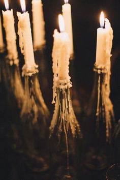 several lit candles in glass vases sitting on a table