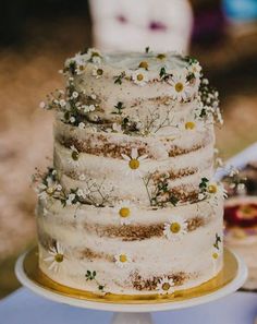 a three tiered cake with flowers on it sitting on top of a white table