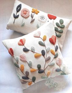 two decorative pillows with embroidered flowers on them