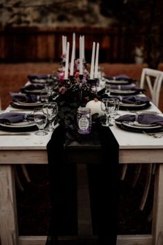 the table is set with black and white place settings, purple napkins, and candles