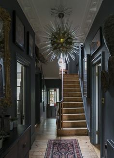 a hallway with stairs and framed pictures on the wall next to an area rug that has been placed in front of it