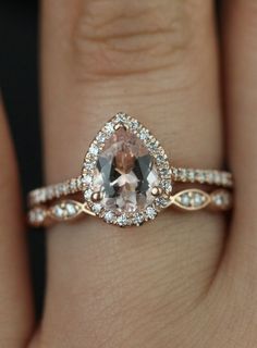 a close up of a person's hand wearing a ring with an oval shaped morganite