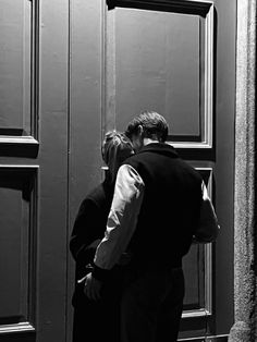 a man and woman kissing in front of a black door with the words love written on it