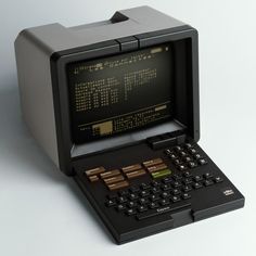 an old computer sitting on top of a white table next to a calculator