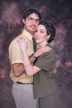 a man and woman are hugging in front of a space background with stars on it