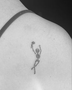 a woman with a skeleton tattoo on her back shoulder and arm holding a flower in the air