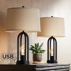 two lamps sitting on top of a table next to a plant