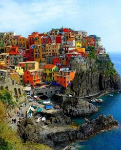 the colorful buildings are perched on top of the cliff by the water's edge