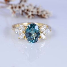 a blue and white diamond ring sitting on top of a table next to some flowers