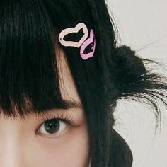 a close up of a person with black hair and two pink scissors in their hair