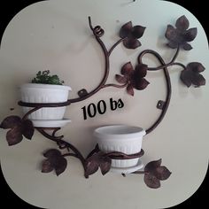 two white flower pots sitting on top of a metal wall shelf next to each other