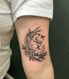 a woman's arm with a cat and flowers tattoo on the left side of her body