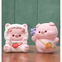 two little pig figurines sitting on top of a wooden table