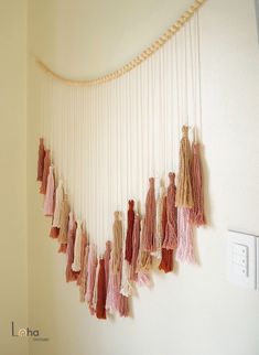 a wall hanging with tassels on it in a room next to a light switch