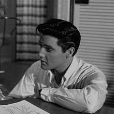 a young man sitting at a table in front of a book with writing on it