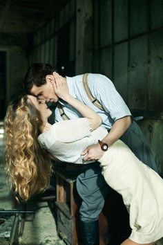 a man kissing a woman on the cheek in front of a wooden table with drawers