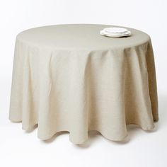 a round table with a white plate on it and a light colored cloth draped over the top