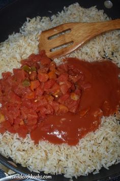 rice and tomato sauce in a skillet with wooden utensils