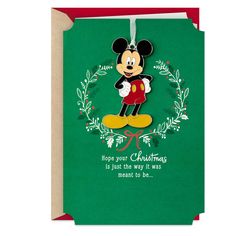 a green christmas card with a mickey mouse hanging from it's front and bottom corner