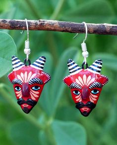 two red and black masks hanging from a tree branch with green leaves in the background