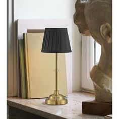 a lamp sitting on top of a wooden table next to a book and a statue