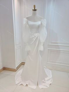 a white wedding dress on display in a room with walls and flooring, including a mannequin's head