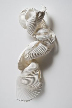 an art piece made out of folded paper on a white surface with one curved object in the middle