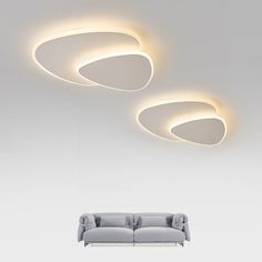 a modern living room with three circular lights on the ceiling and two couches in front of it