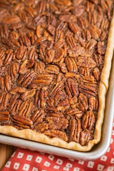 a close up of a pecan pie on a red and white cloth with a wooden spoon