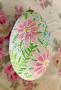 an ornament hanging from the ceiling with pink flowers on it and green leaves