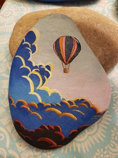 a painted rock with a hot air balloon in the sky